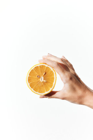 Hand holding an orange slice on a white backgroundの写真素材