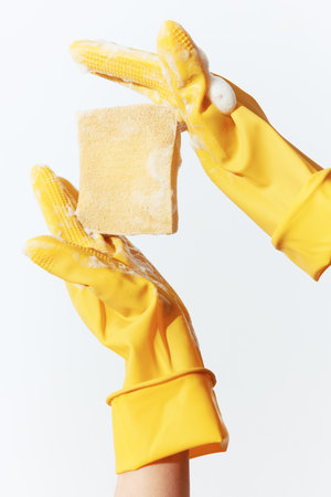 Two hands in yellow rubber gloves holding a sponge on a white backgroundの写真素材