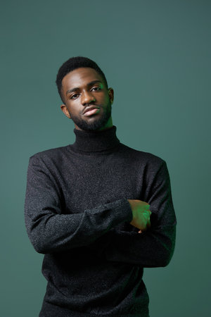 Confident african american man in black turtleneck sweater standing with arms crossed against a neutral backgroundの写真素材