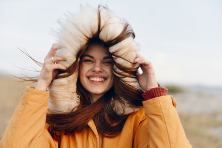 Fashionable woman in yellow jacket smiling and holding her head up in luxurious fur coat