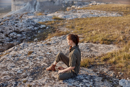 Woman sitting on cliff overlooking valley and mountains in background, travel adventure and exploration conceptの写真素材