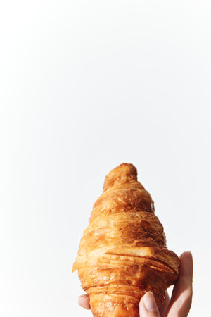 Person holding a croissant on a white background with copy space in the middle