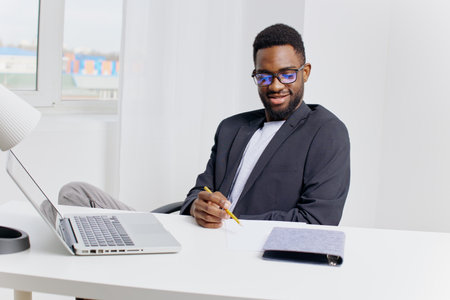 Focused professional man working at desk with laptop and pen, engaged in thoughtful task or projectの写真素材