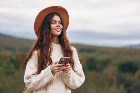 Mountain Adventure: Smiling Woman in Hat, Capturing Selfie on Mobile Phone while Hiking in breathtaking Landscapeの写真素材