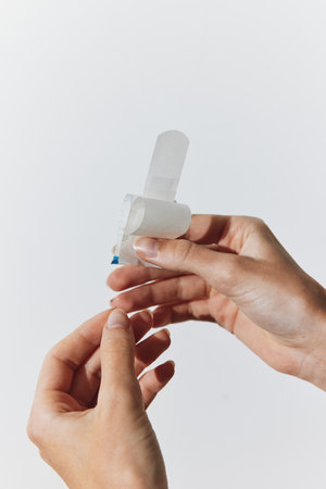 Two people with white bandages on their fingers holding small pieces of plasticの写真素材