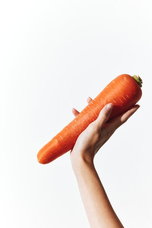 A person holding a large carrot, isolated on white background with copy space