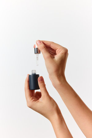 Hands holding small bottle with dropper on white background, copy space available