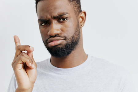 Frustrated man with a beard pointing angrily to his temple, indicating confusion or disbelief in a...