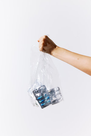 Person holding a bag full of plastic bottles against a white background with copy space