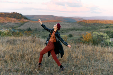 Woman feeling empowered and free standing with arms raised in the middle of a vast fieldの写真素材