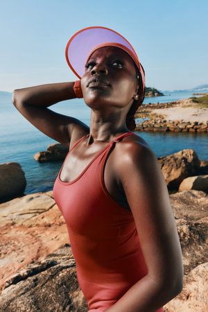 Confident woman in sportswear posing by the seaside, showcasing a healthy lifestyle and empowerment...
