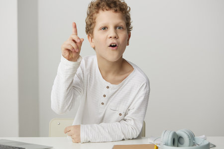 Smiling Boy Learning with Laptop at Home A cute Caucasian boy, sitting at a modern desk in his cozy home, is engrossed in elearning and online education With a happy expression on his face, he isの写真素材