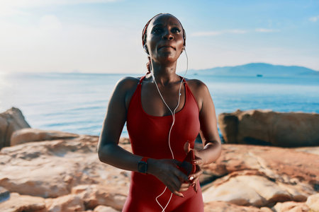 Woman exercising by the seaside in a red outfit, enjoying the calm ocean view, capturing a moment of...