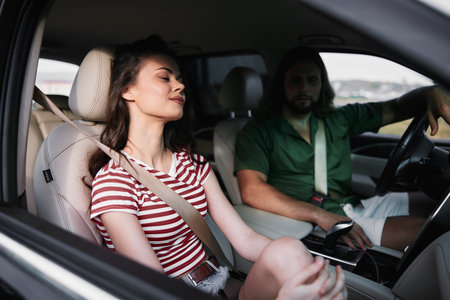 Young couple sitting in a car, enjoying a moment together, with the woman relaxed and the man...
