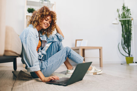 Modern Lifestyle: Smiling Woman Typing on Laptop in Cozy Living Room, Working from Homeの写真素材