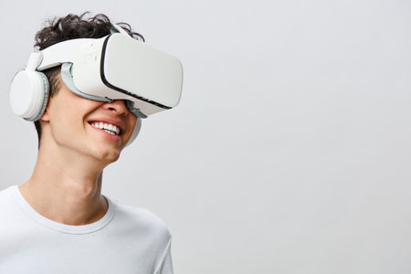Virtual reality experience, smiling young male, wearing VR headset, white headphones, light...