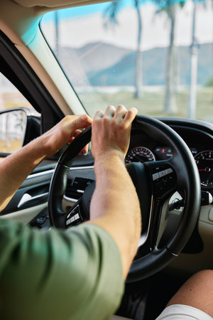 Person driving a car with both hands on the steering wheel, showing focus and control Scenic view...