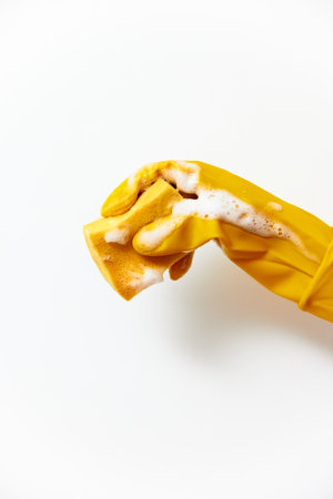 Clean yellow rubber glove with clean written on it, held by a hand on a white surfaceの写真素材