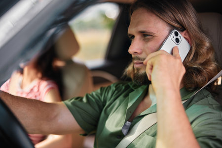 Man driving a car while talking on the phone, showing focus and concentration in a relaxed interior environmentの写真素材