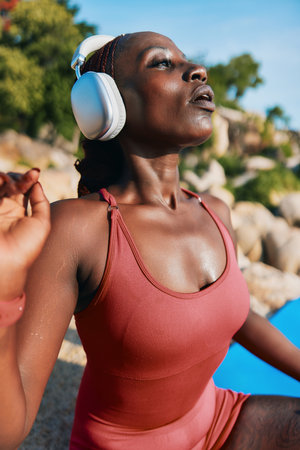Young woman in athletic wear enjoying music outdoors by the waterの写真素材