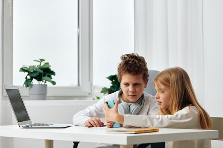 Happy Caucasian kids studying and playing games on laptops and tablets in a cozy living room...