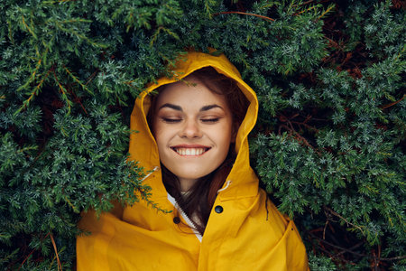 A Happy Woman in a Sunny Yellow Raincoat Enjoying Nature in the Lush Green Forestの写真素材