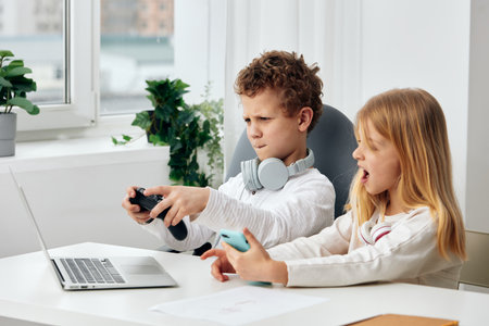 Children studying together online on their laptops at home, immersed in elearning and enjoying their...