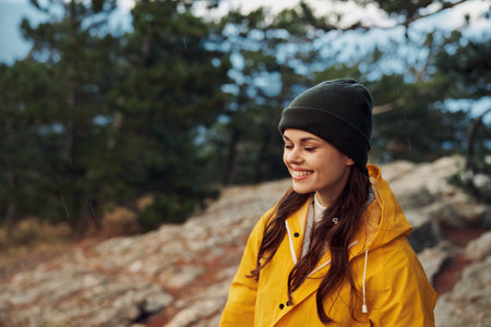 A woman in a yellow raincoat smiling while standing on a rocky hill in the woods enjoying the Natures Serenityの写真素材