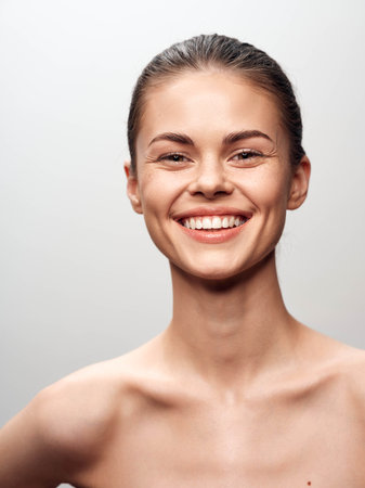 Beautiful young woman smiling portrait on gray background with natural lighting and soft focusの写真素材