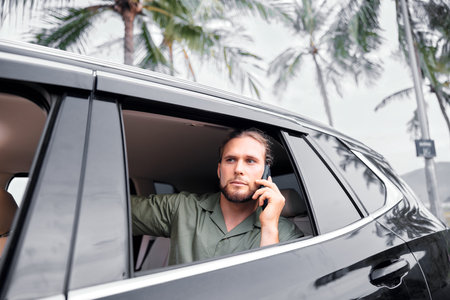 Man talking on the phone from a car window surrounded by palm trees