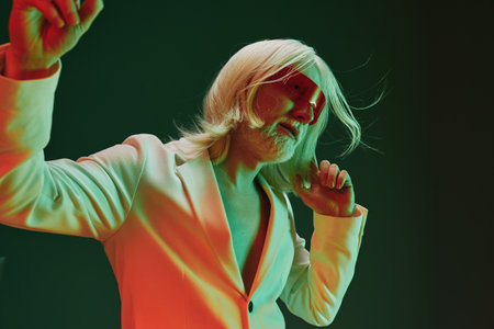 Stylish man in a white suit with red tinted sunglasses dancing against a green backdrop, showcasing...