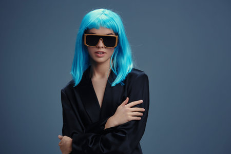 A woman with blue hair wearing sunglasses and a black dress poses against a gray background, exuding a stylish and edgy vibeの写真素材