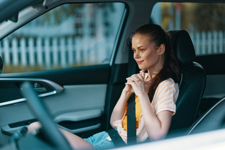 woman in a car, smiling, casual attire, interior, happy expression, focused on the road, modern vehicle backdrop, relaxed atmosphere, summer vibes, bright daylightの写真素材