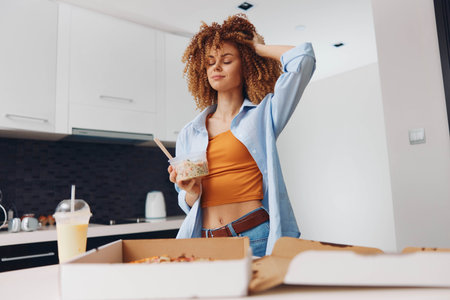 Woman with curly hair standing in front of pizza box and cup of coffee in a cozy settingの写真素材