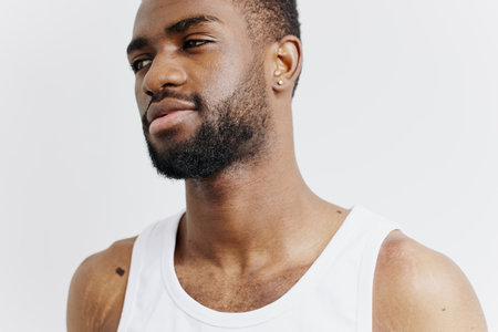 Thoughtful african american man in white tank top gazing into distance, contemplating future decisions and possibilitiesの写真素材