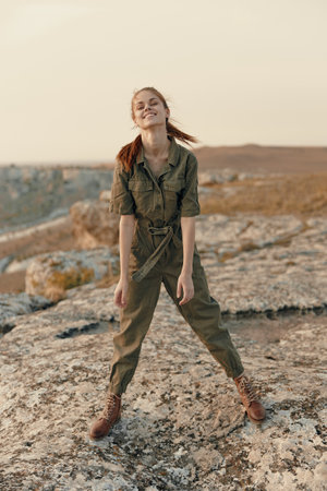 Young woman embracing nature on top of a rock with arms raised in air experiencing travel and adventure in scenic beautyの写真素材