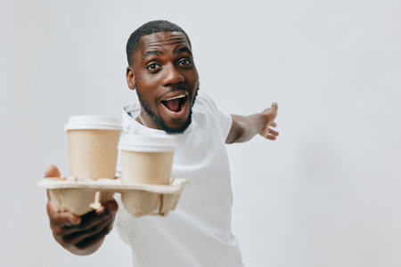 Smiling man holding coffee cups, joyful expression, casual attire, neutral background, conveying excitement and happiness with beverages Perfect for lifestyle, coffee, and positivity searchesの写真素材