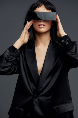 Virtual reality glasseswearing woman in a black suit, looking directly at the camera, embodying a futuristic, techsavvy professional appearanceの写真素材