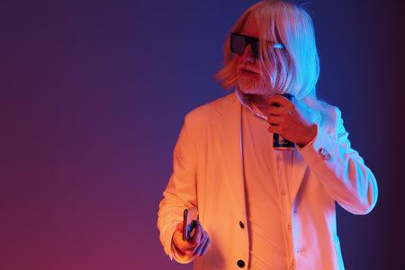 Trendy elderly man with long white hair in stylish sunglasses holding a can Modern background with vibrant colors creating a playful atmosphere Perfect for lifestyle and fashion themesの写真素材