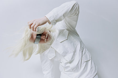 Model in a white outfit posing against a minimalistic gray background, showcasing avant garde fashion with a creative twist Dynamic movement adds energy to the shotの写真素材