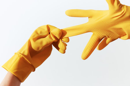 Pair of yellow rubber gloves held by hands on white background with help written on themの写真素材