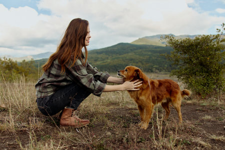 Woman enjoying dog company in picturesque field with majestic mountains in the backgroundの写真素材