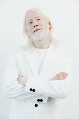 Confident man in a white suit against a clean, bright background, showcasing a modern and stylish look, with a relaxed pose and a serene expressionの写真素材