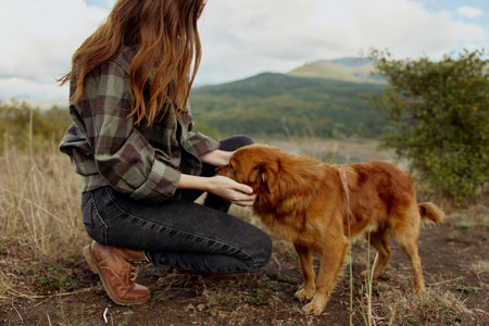 A woman enjoying peaceful moment with her furry companion in a scenic mountain field retreatの写真素材