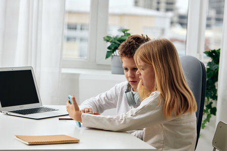 Happy Caucasian boy and girl studying together at home They are sitting at a table, fully engaged in...