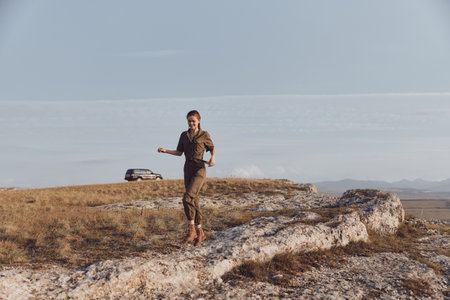 Woman standing on rock with car in background travel adventure with breathtaking views and scenic...