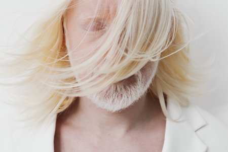 Portrait of a person with flowing blonde hair, eyes closed, showcasing soft features on a white background The serene expression captures a moment of introspection and tranquilityの写真素材