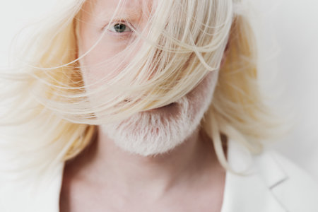 portrait, confident, mature man with long blonde hair, partially obscured face, soft focus on white background, inviting serenity and introspection Emotional expression conveys depth and intrigueの写真素材