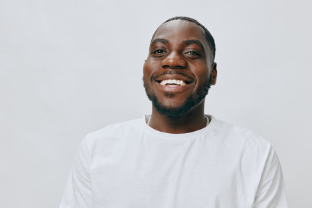 Smiling man in white t shirt, joyful expression, neutral background, showcasing happiness and...