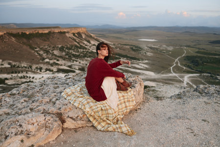 Woman relaxing on top of rock with blanket, enjoying serene outdoor moment